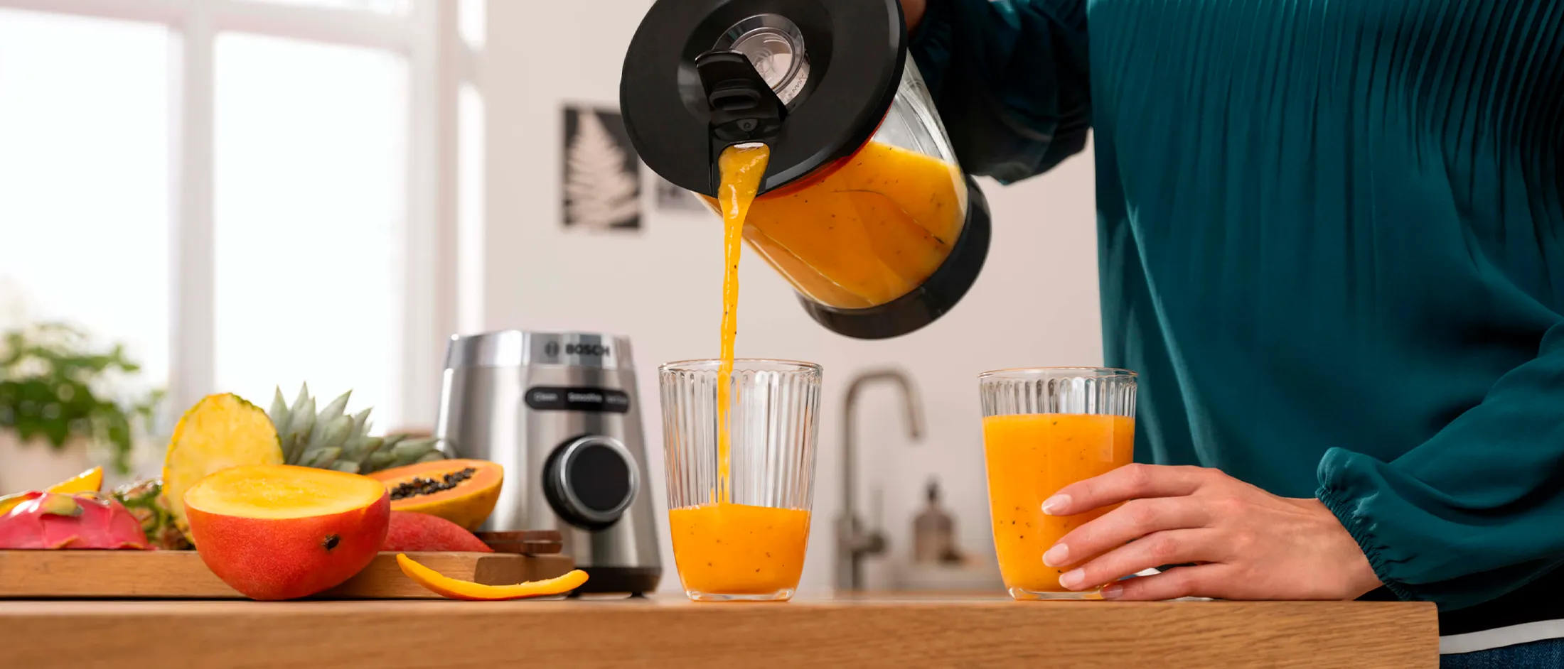 Uma mulher vertendo smoothie do liquidificador Bosch VitaPower Serie 4 em um copo.
