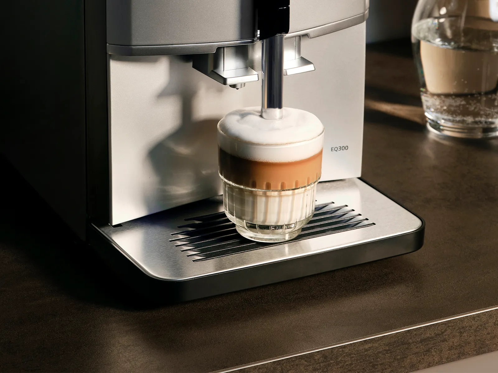 Visning af den fuldautomatiske espresso-/kaffemaskine EQ300 på et køkkenbord.