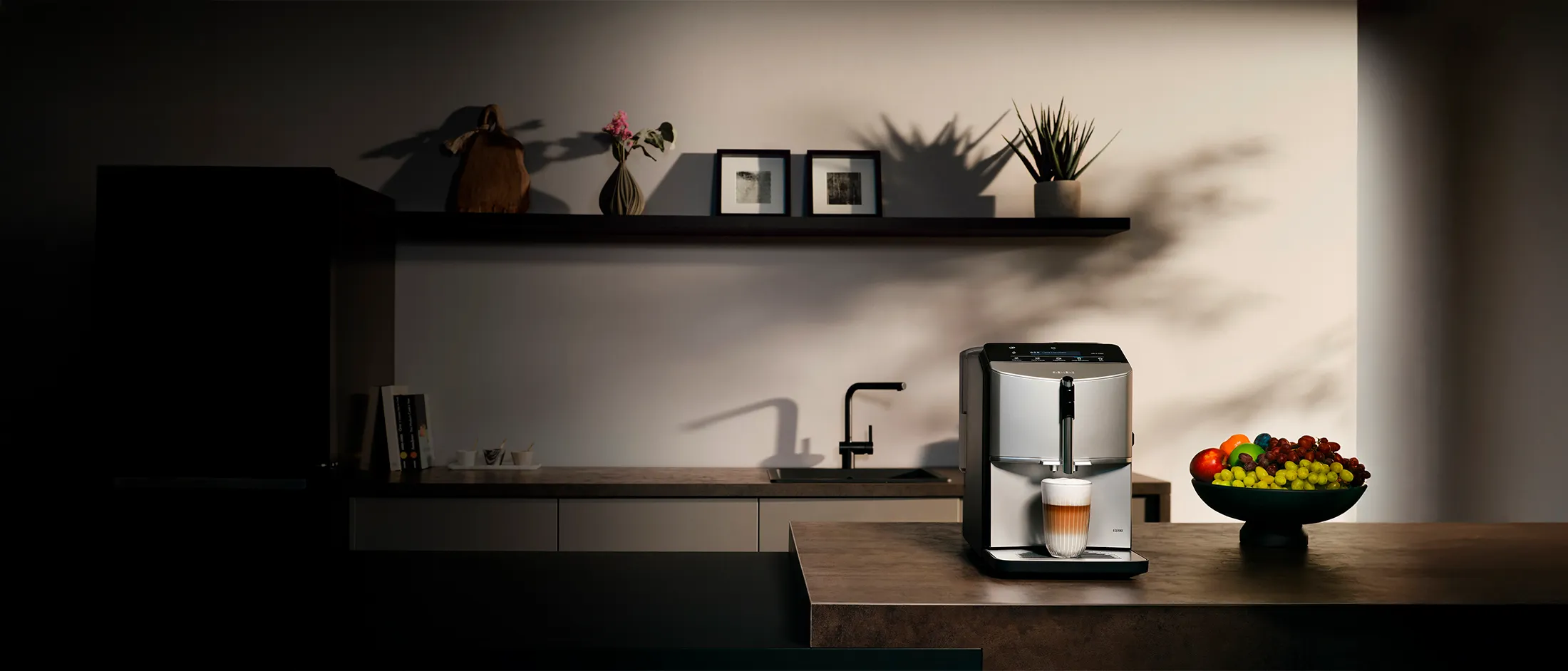 Cuisine avec la machine à espresso entièrement automatique EQ300 sur l'île de cuisine, un verre de latte macchiato est sous la prise.