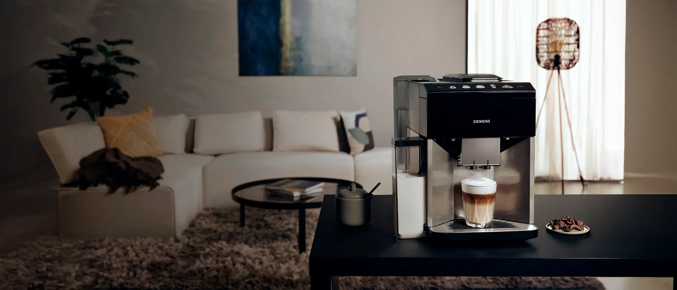 A EQ500 Siemens coffee machine on a table preparing a latte in a modern living room.
