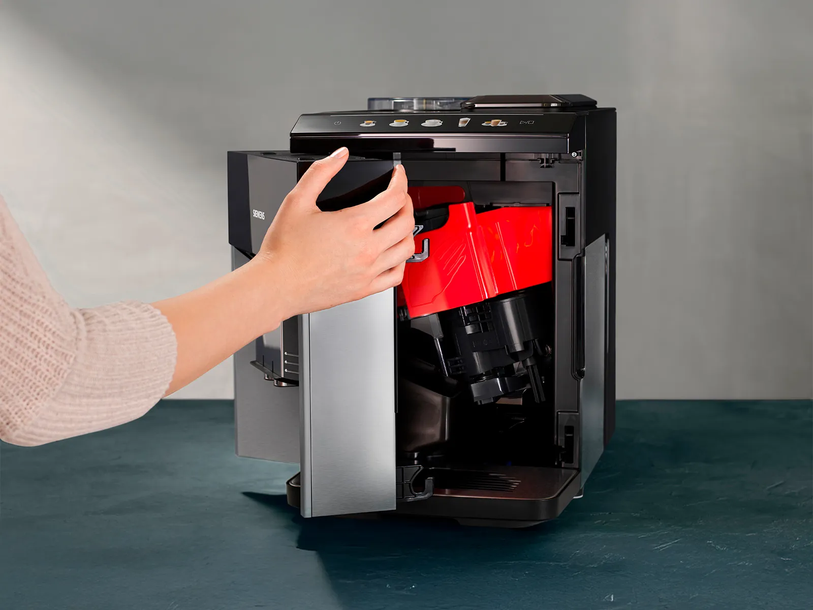 Jemand öffnet die Serviceklappe an der Vorderseite des EQ500 Kaffeevollautomaten. Du bekommst einen Blick ins Innenleben der Maschine.