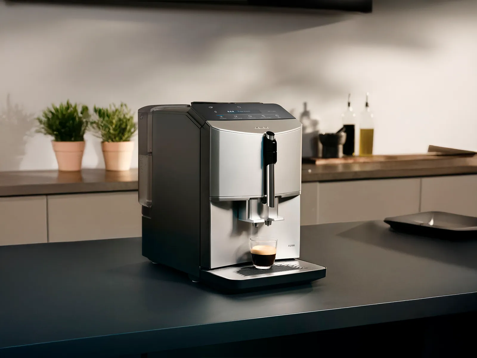 Un espressor automat Siemens EQ300, de culoare gri, pe blatul din bucătărie, pregătind o ceașcă proaspătă de cafea.