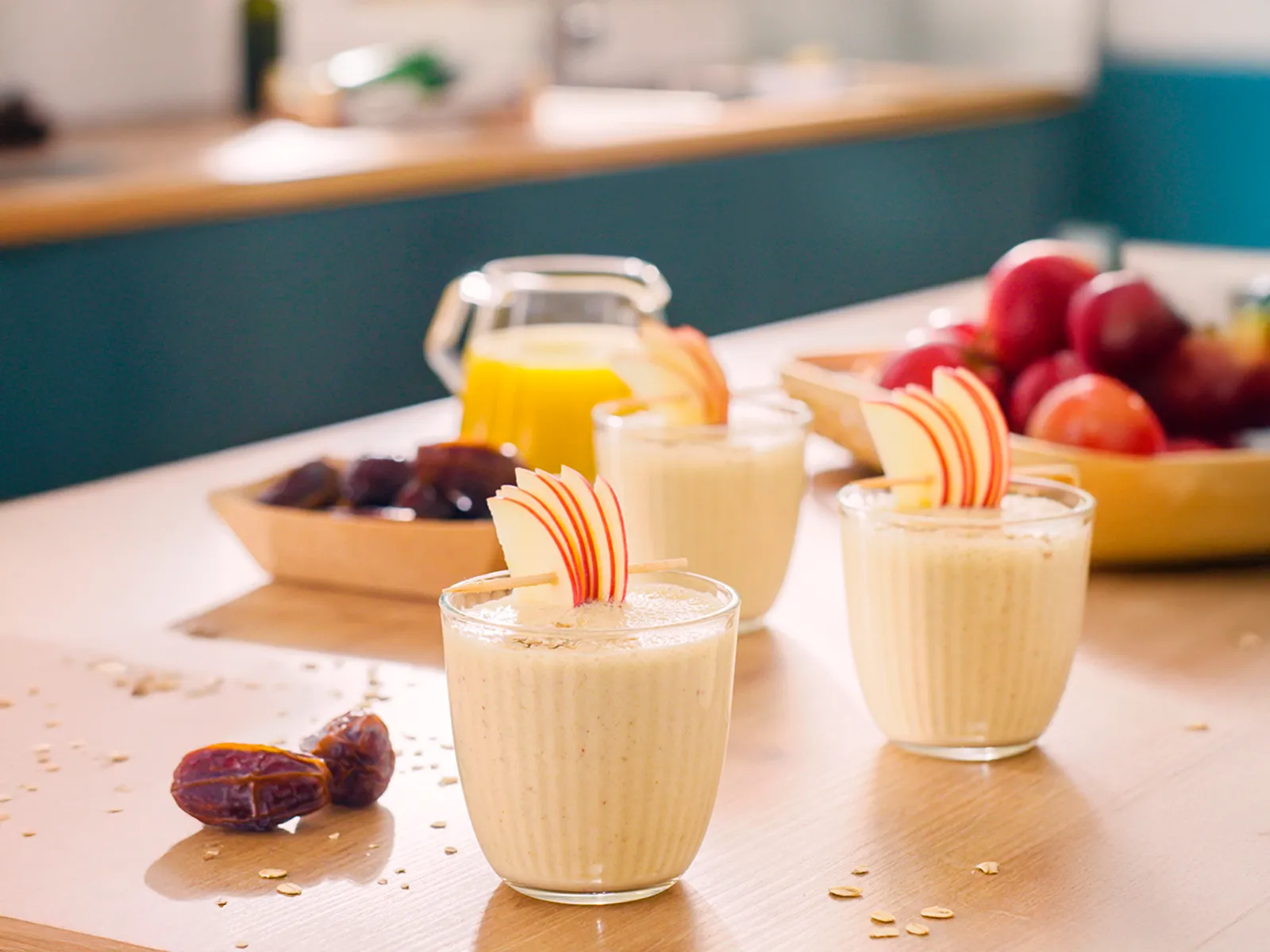 Млечни шейкове в чаши на кухненския плот, гарнирани с парчета плодове.