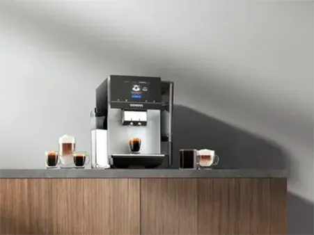 A Siemens coffee machine on a countertop, with four coffee cups filled with various espresso drinks.