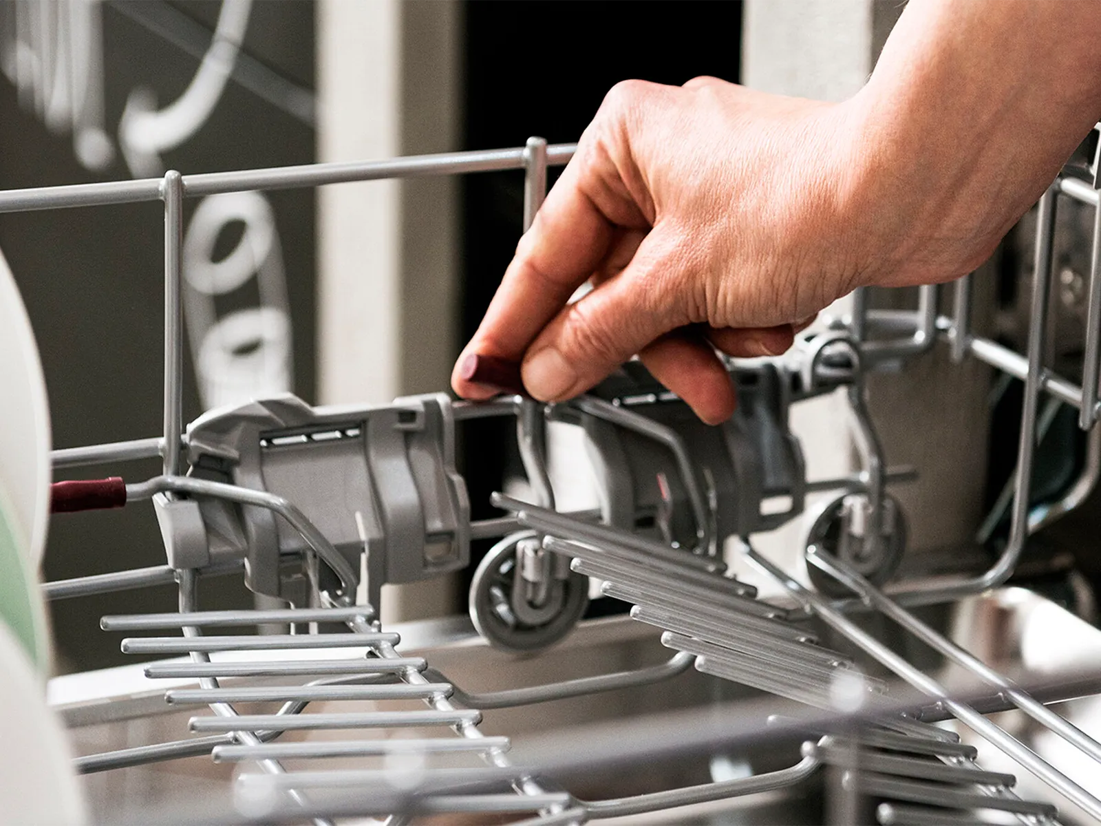 A person’s hand adding accessories to a dishwasher rack.