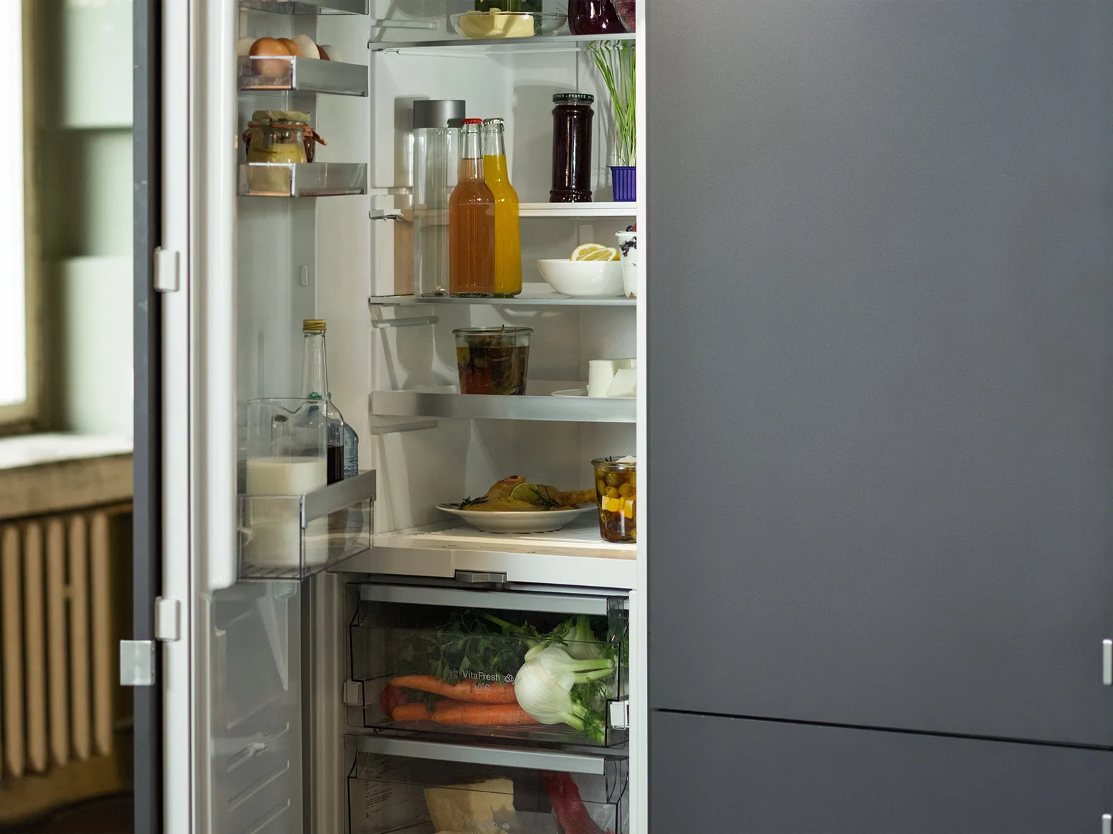 A built-in open fridge-freezer combination to the right of a large window.