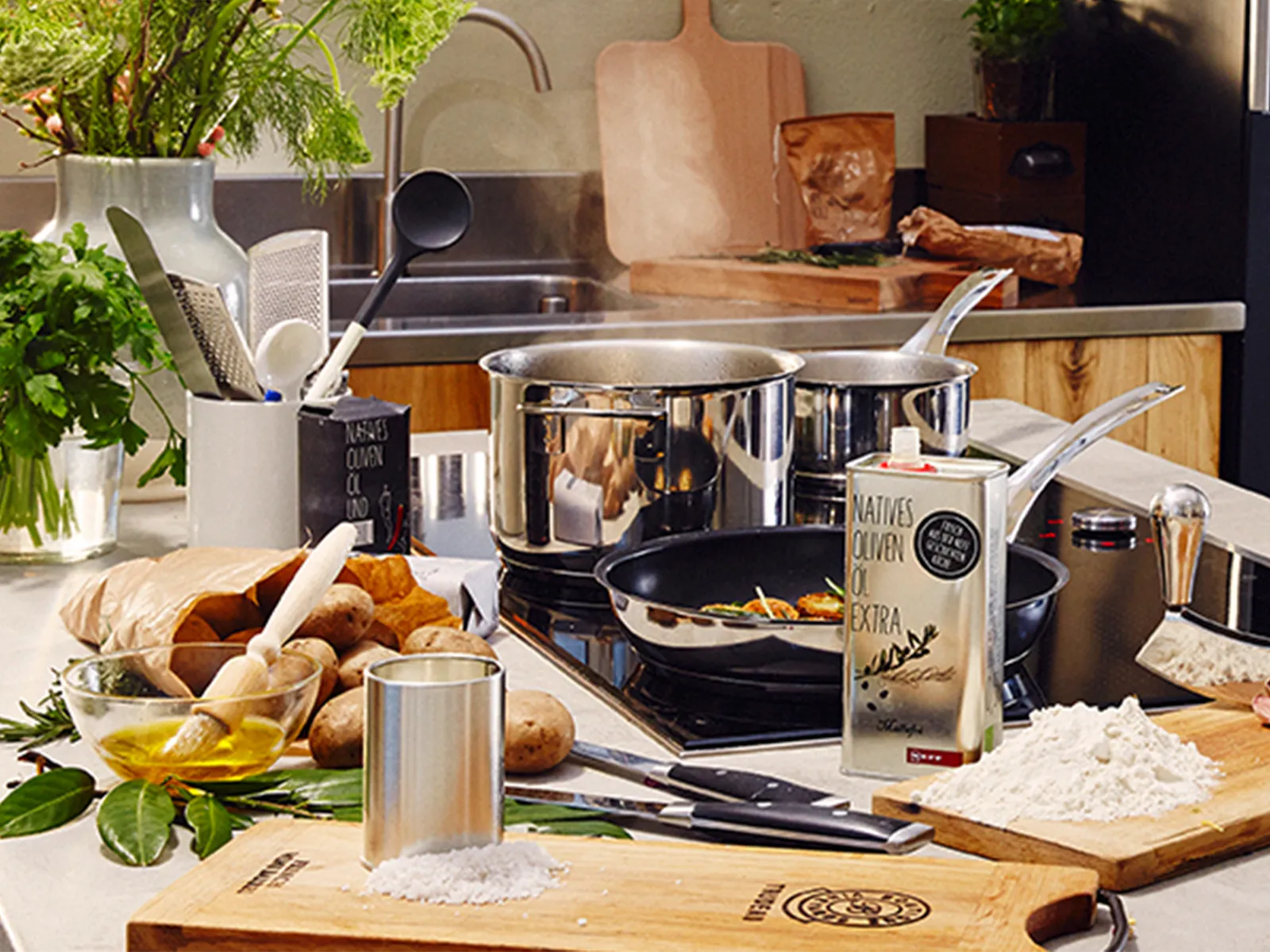 A selection of additional cooking utensils and care products assembled on a kitchen island in front of a hob in use