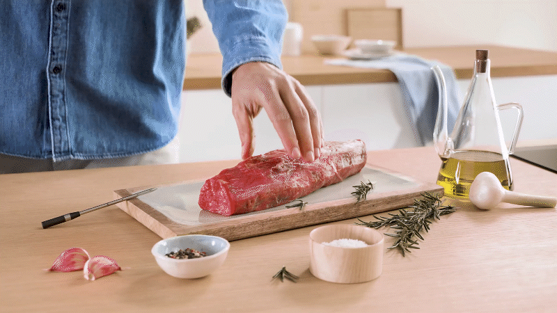 Vorbereitung eines Fleischbratens auf einem Holzbrett mit dem kabellosen Bosch PerfectRoast Fleischthermometer.