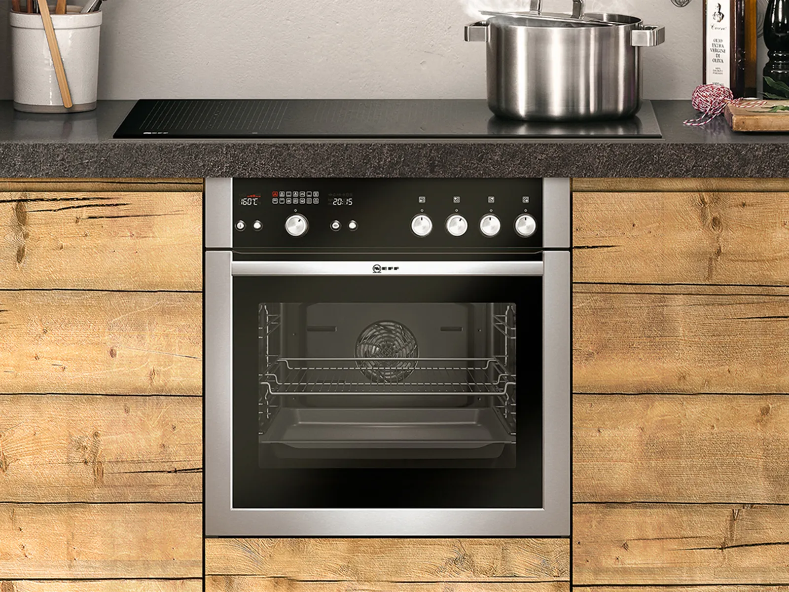 A cooker over with stainless steel dials built-in under cooktop in wooden kitchen 