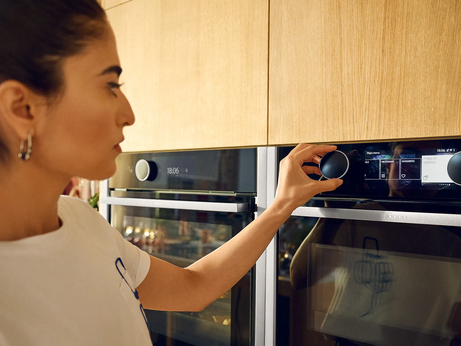 Woman twisting Twist Pad Flex on the oven shown in Metallic Silver, wood kitchen 