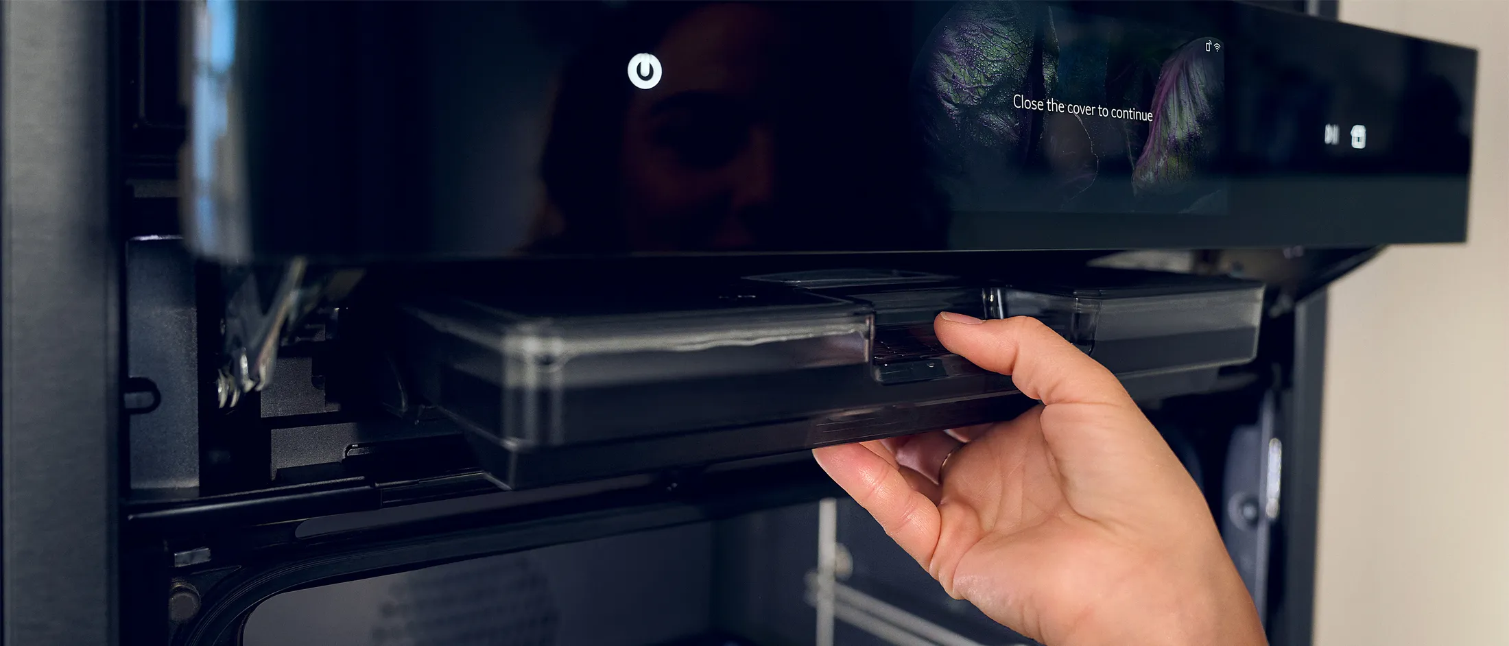 Hand inserting water tank into steam oven, lifted display