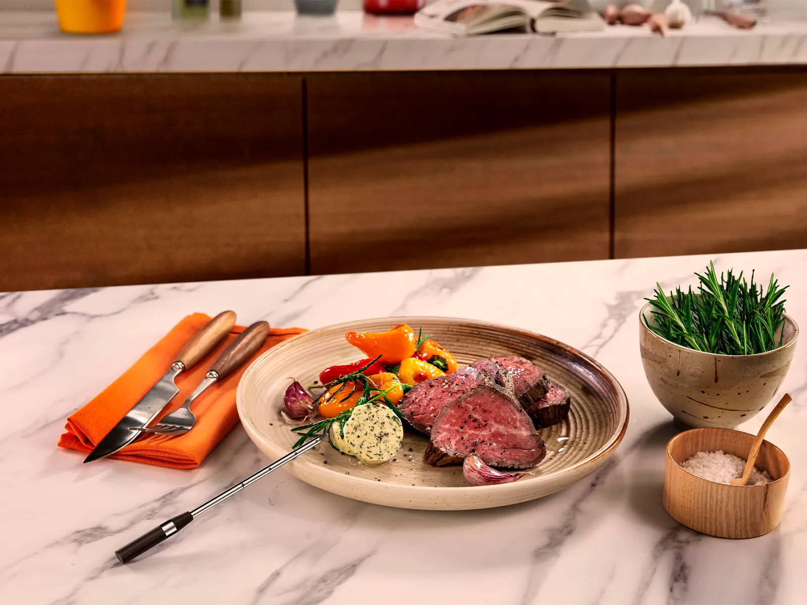 En tallrik med perfekt stekt kött med grönsaker och kryddsmör på en köksbänk i marmor.