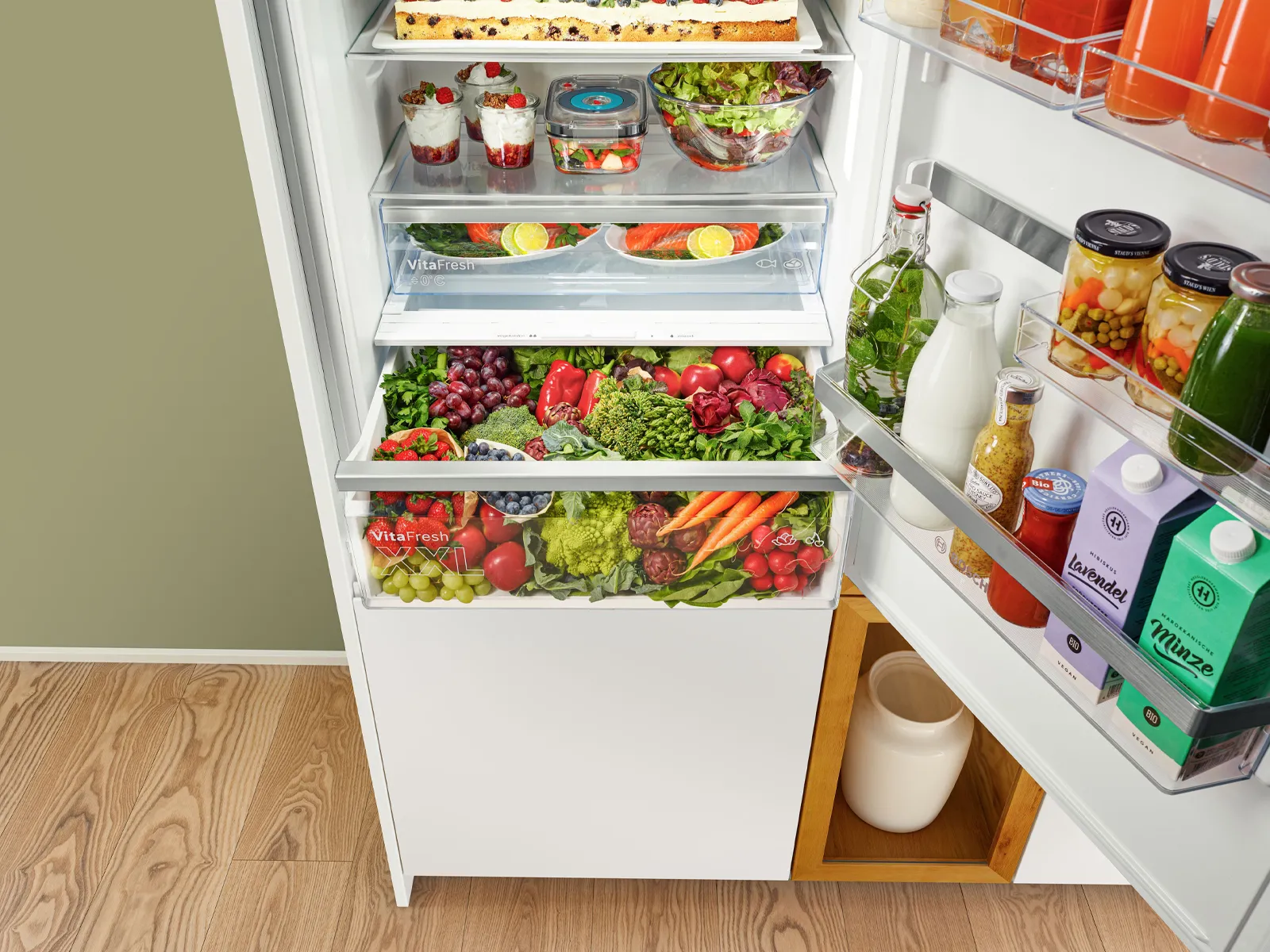 Hästi organiseeritud külmik, mis on täis värskeid toite, jooke ja maitseaineid läbipaistvates sahtlites ja riiulitel.