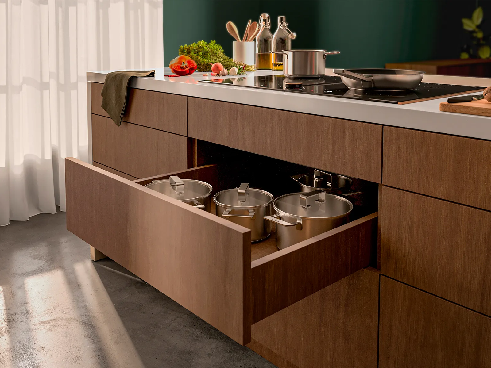View of a hob with integrated ventilation, under which a drawer with pots and pans can be seen