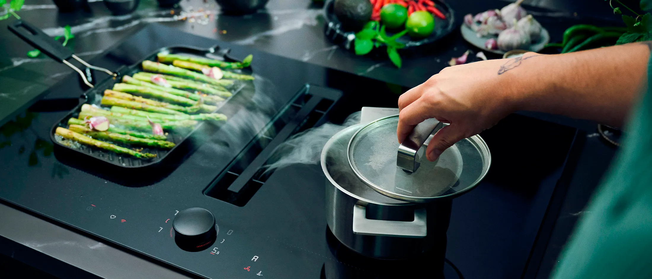 View of a hob with integrated ventilation system, drawing in the steam coming from a pan and a pot