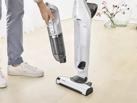 Person using a Bosch cordless vacuum cleaner on a hardwood floor.