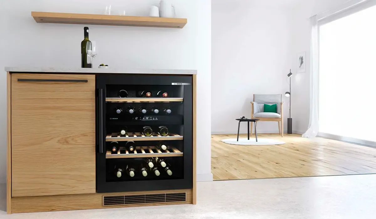 Large freestanding wine cabinet with several wines bottles on wooden racks next to a modern kitchen nook