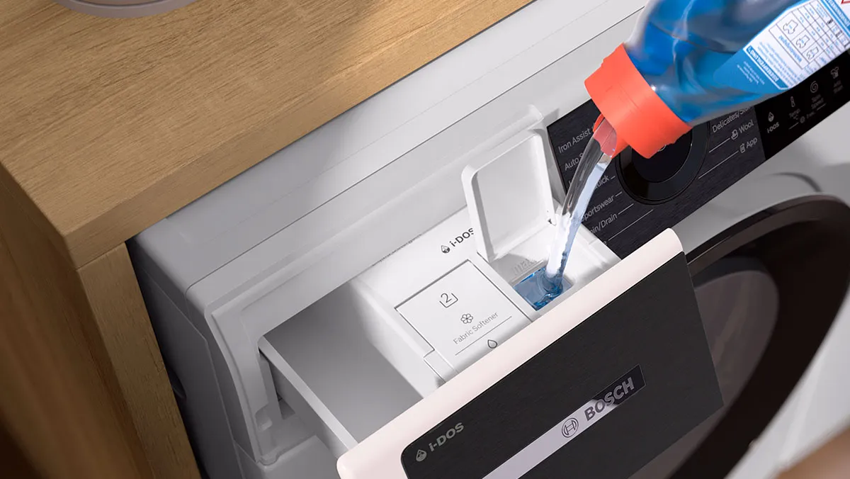En person häller tvättmedel i tvättmedelsfacket på en Bosch-tvättmaskin och lyfter fram dess eleganta design och funktionalitet.