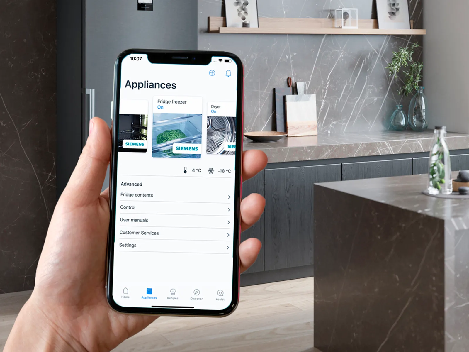 Detalle de una persona en una cafetería controlando sus electrodomésticos desde el móvil mediante la app Home Connect.