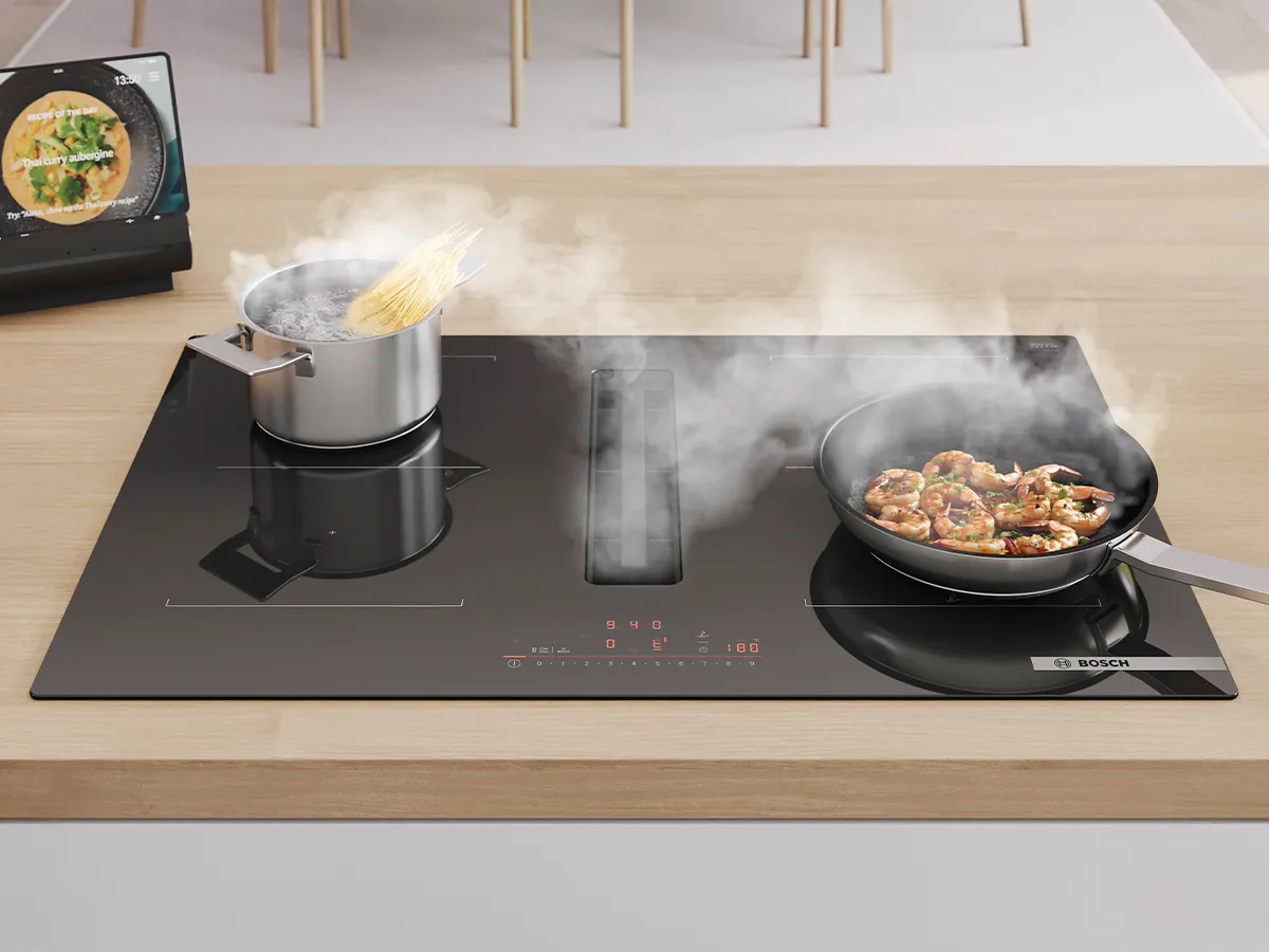 Close up of pans cooking on vented hob whilst it extracts steam