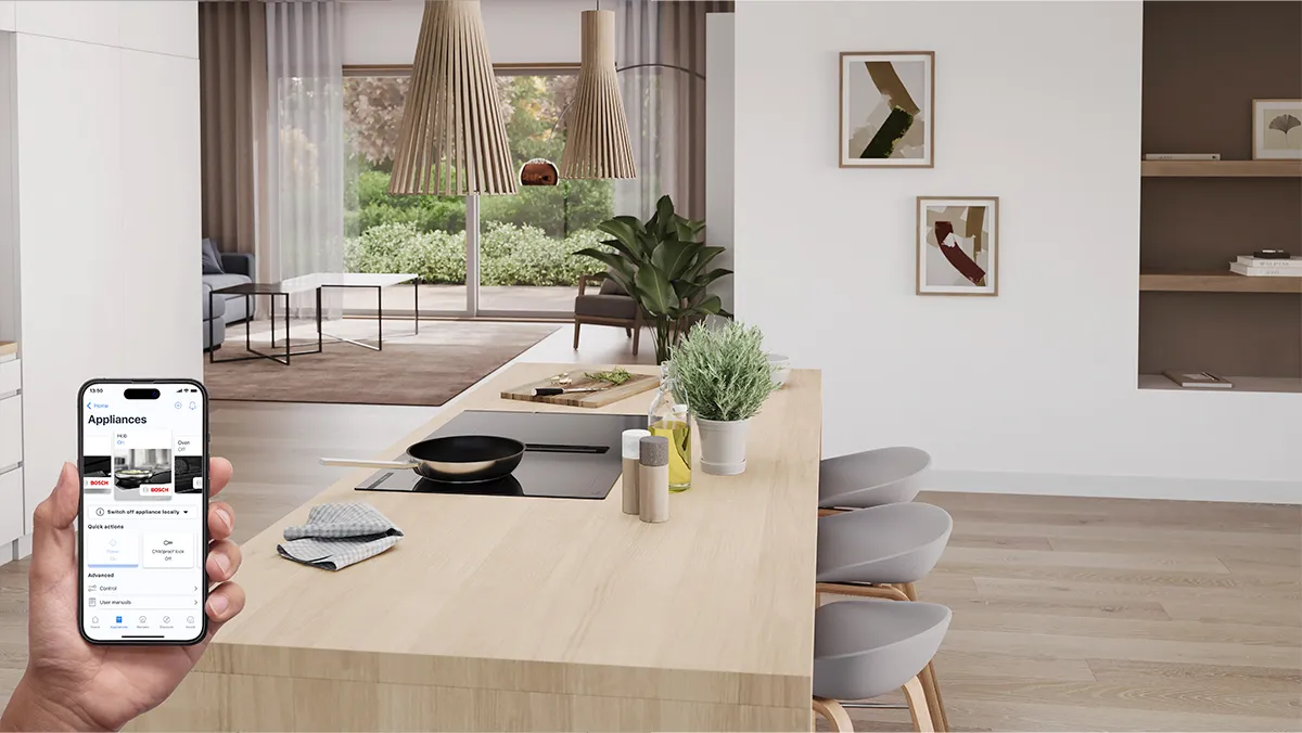 A modern kitchen featuring a smartphone displaying appliance settings, a wooden island, plants, and stylish decor with natural light.