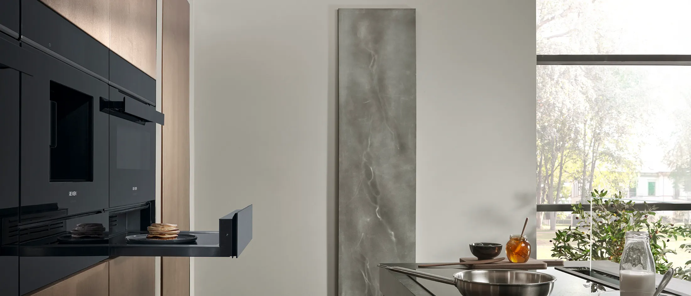 Siemens built-in warming drawer extended, seamlessly integrated into a modern kitchen with sleek appliances.