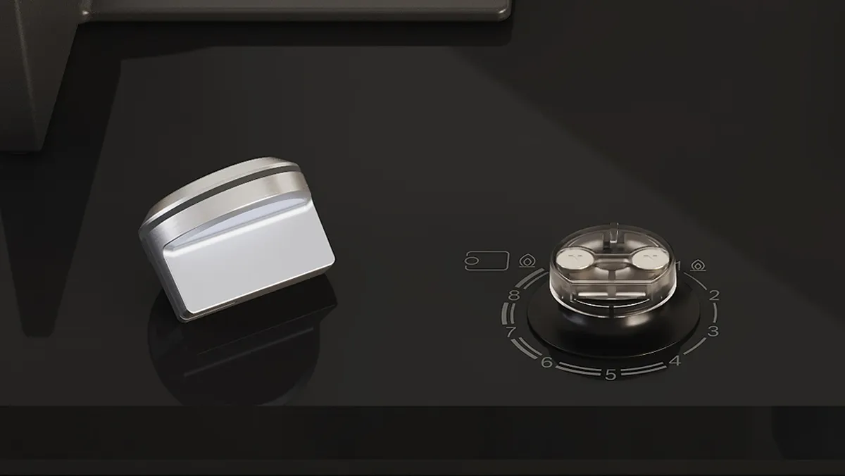 Close-up of a sleek black stovetop featuring a metallic control knob and a round burner indicator.