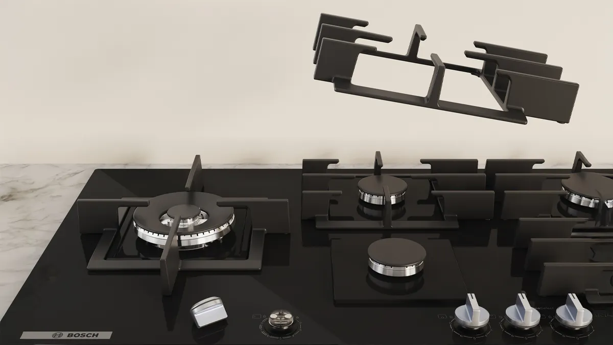 A sleek black gas stovetop featuring multiple burners, with a griddle grate hovering above it.