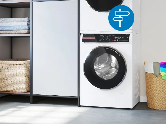 A white Bosch front-loading washing machine with a laundry basket next to it. A single, colorful striped sock is placed on top of the machine. A blue circular icon with a white directional sign is overlaid on the right.