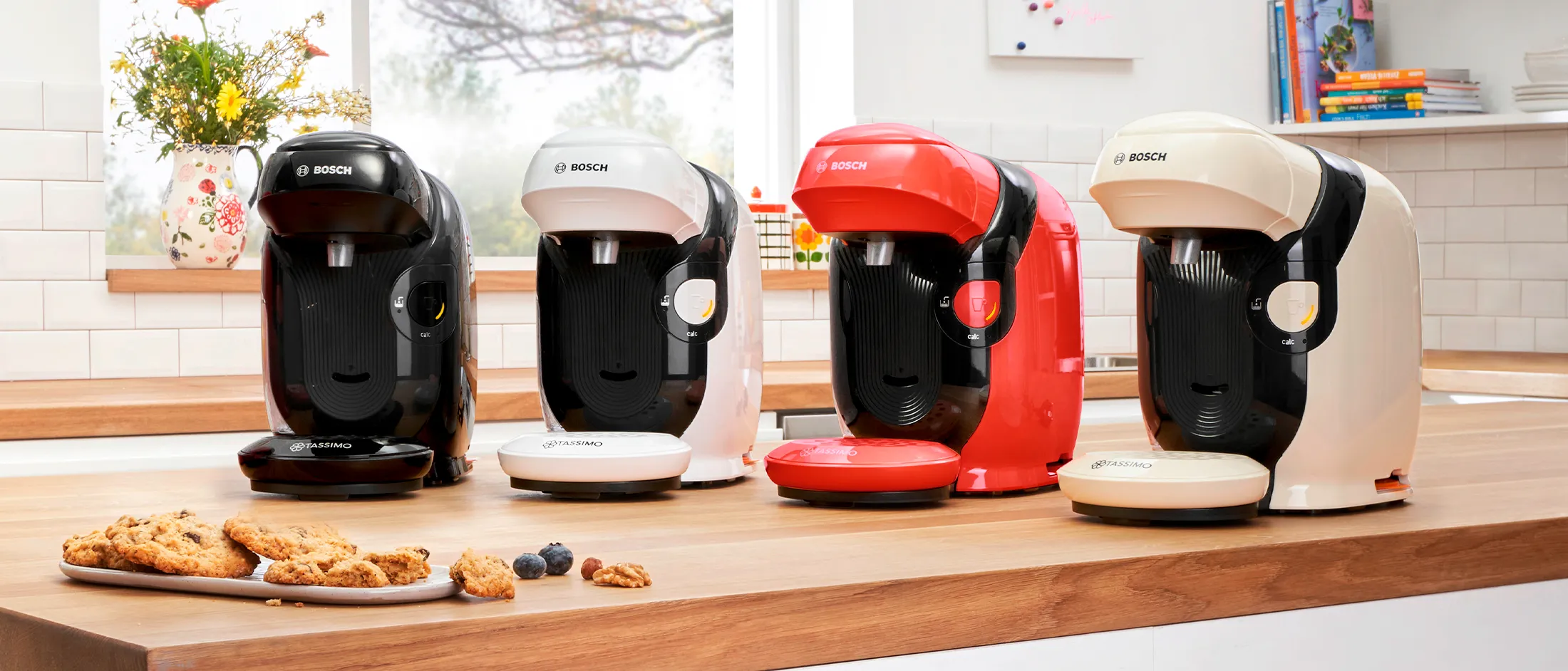 TASSIMO STYLE friendly coffee machines in different colours on a kitchen worktop.