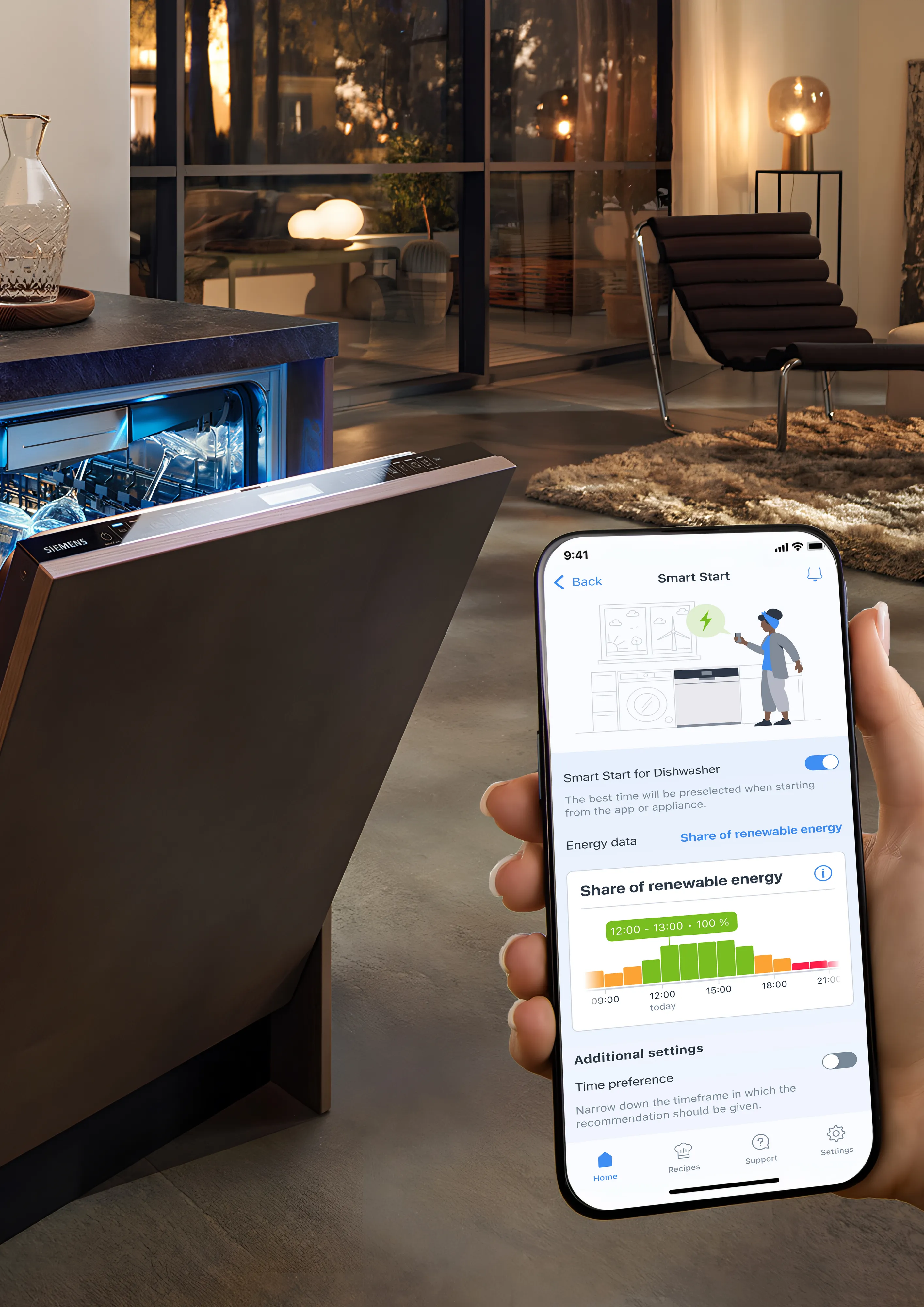 En person holder en smartphone med en app, der viser energidata for en opvaskemaskine. Opvaskemaskinen står åben i et moderne køkken- og stueområde med stilfuld indretning.