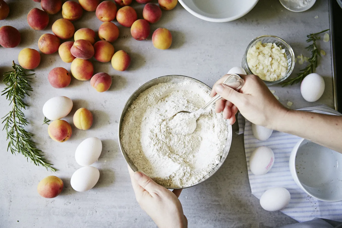 Mixing bowl filled dry ingredients and loose apricots in the background