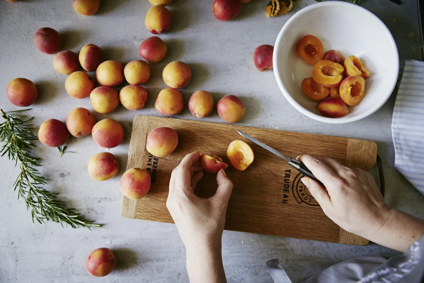 Person slicing apricots on wooden board