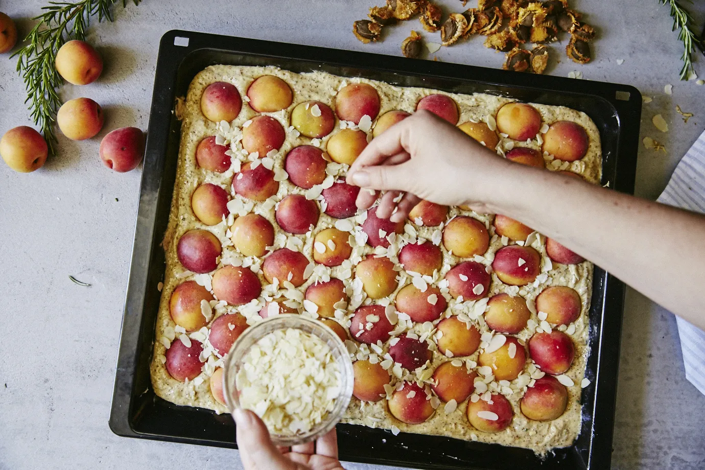 Person putting flaked almonds on cake