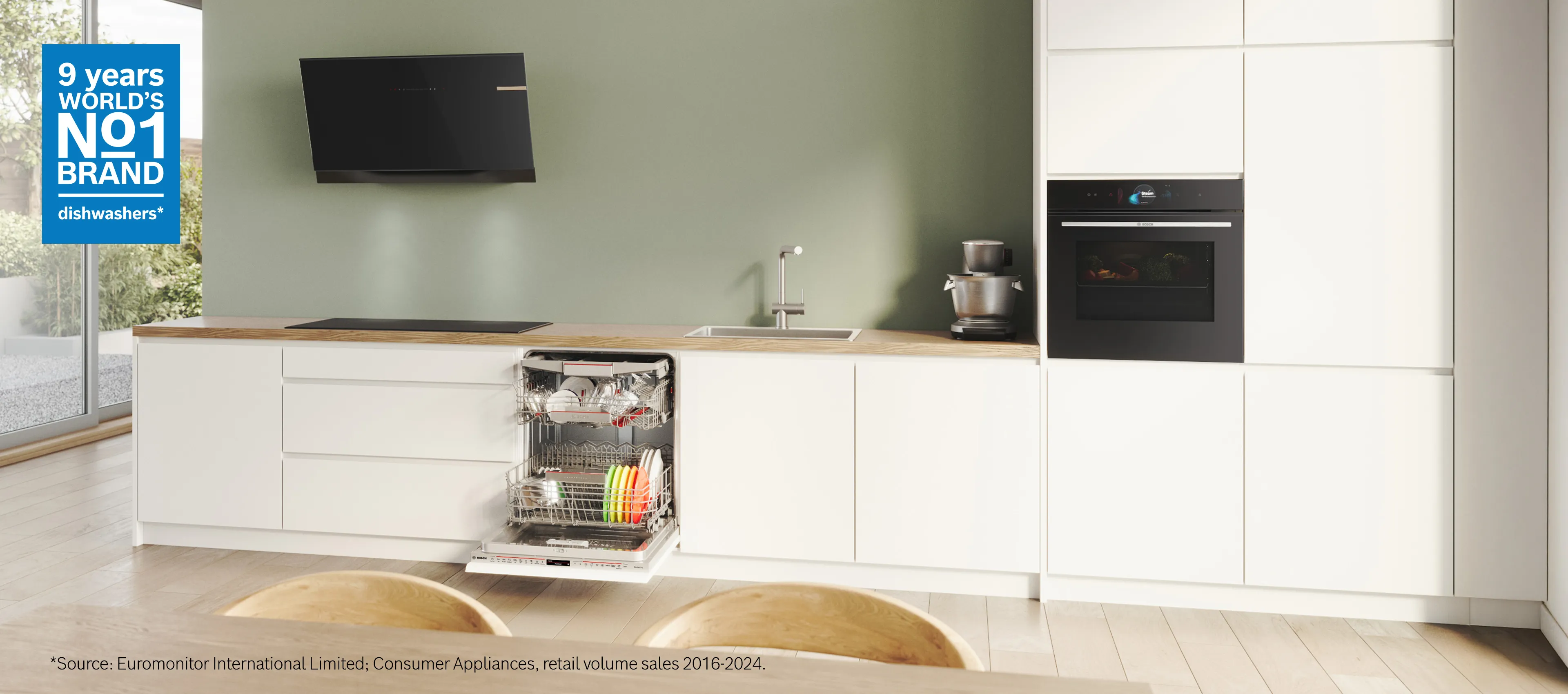 Bosch food processor with touch display surrounded by various fresh vegetables on a table.