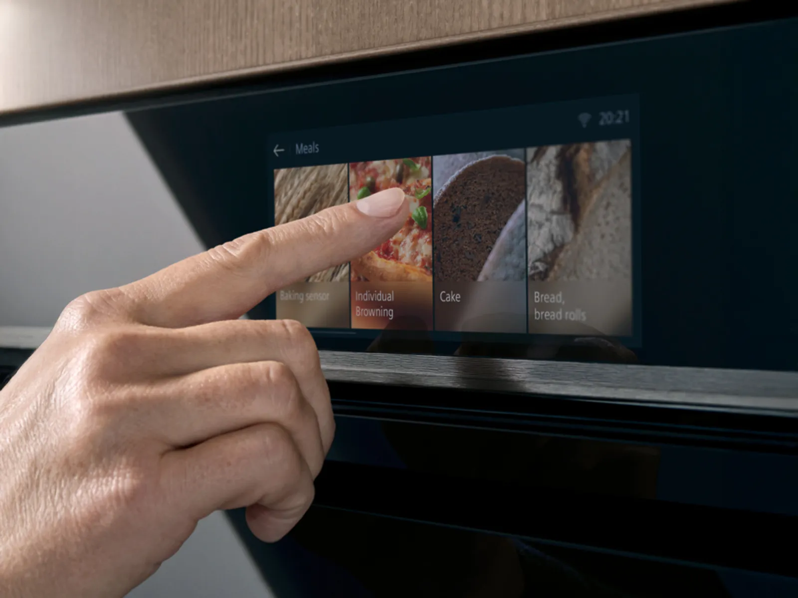 En hånd trykker på et TFT-Touchdisplay på en indbygget Siemens ovn