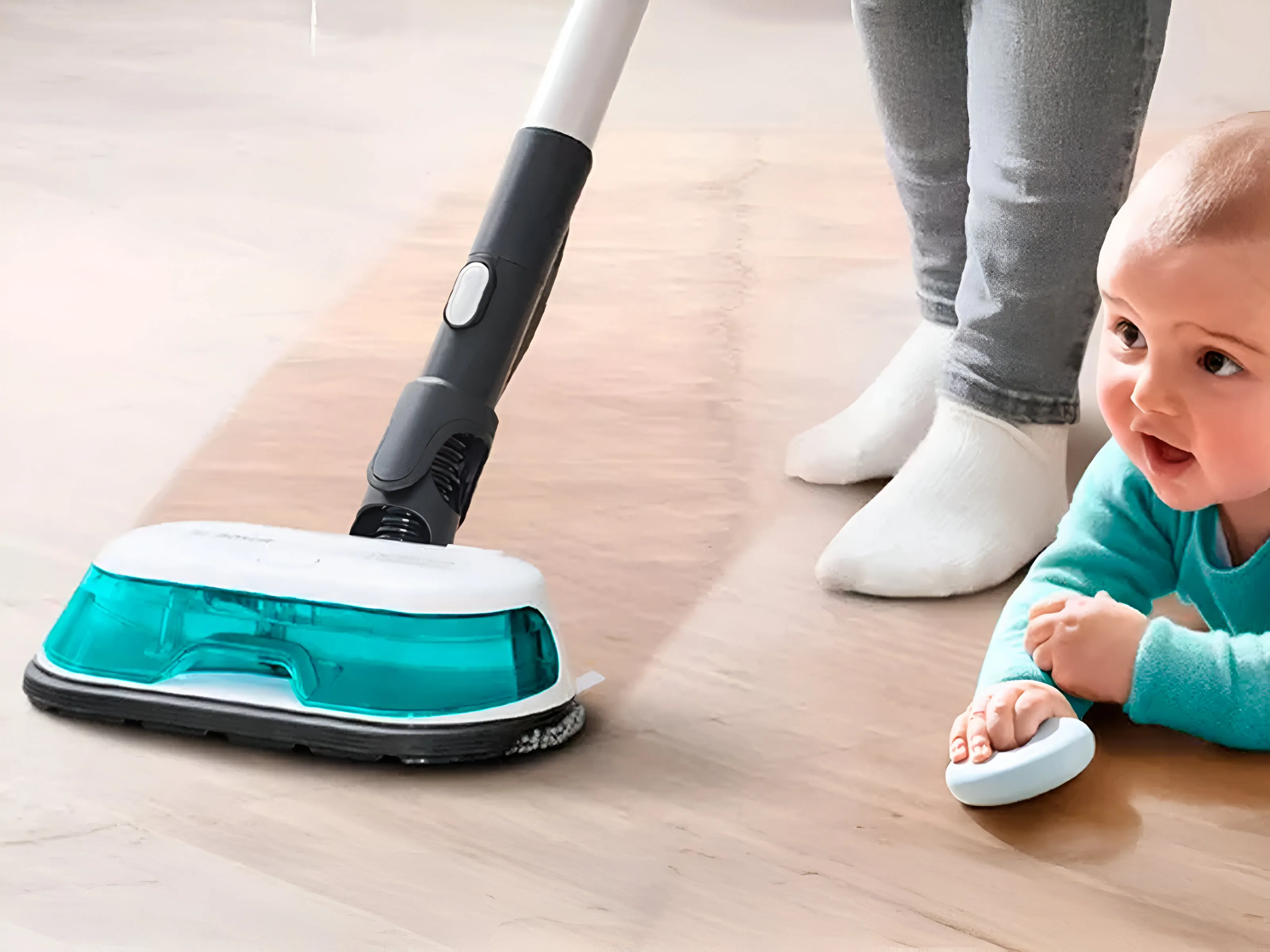 Mopovací vysavač čistí podlahu, zatímco si dítě hraje poblíž.