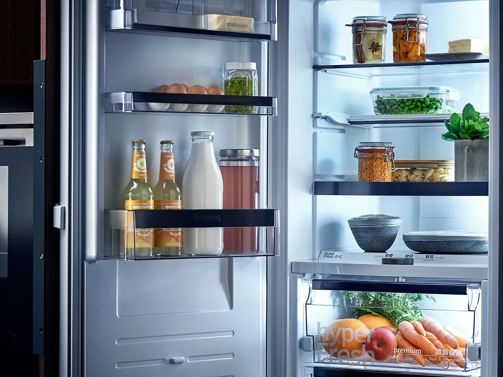 Interior del compartimento refrigerador de un frigorífico Siemens, con agradable iluminación LED y diferentes tipos de alimentos frescos.