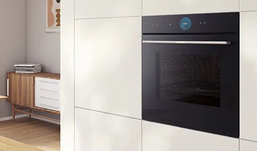 Ein eleganter schwarzer Einbaubackofen in den weißen Schränken einer modernen Küche, ausgestattet mit einem digitalen Bedienfeld und einer Glastür.