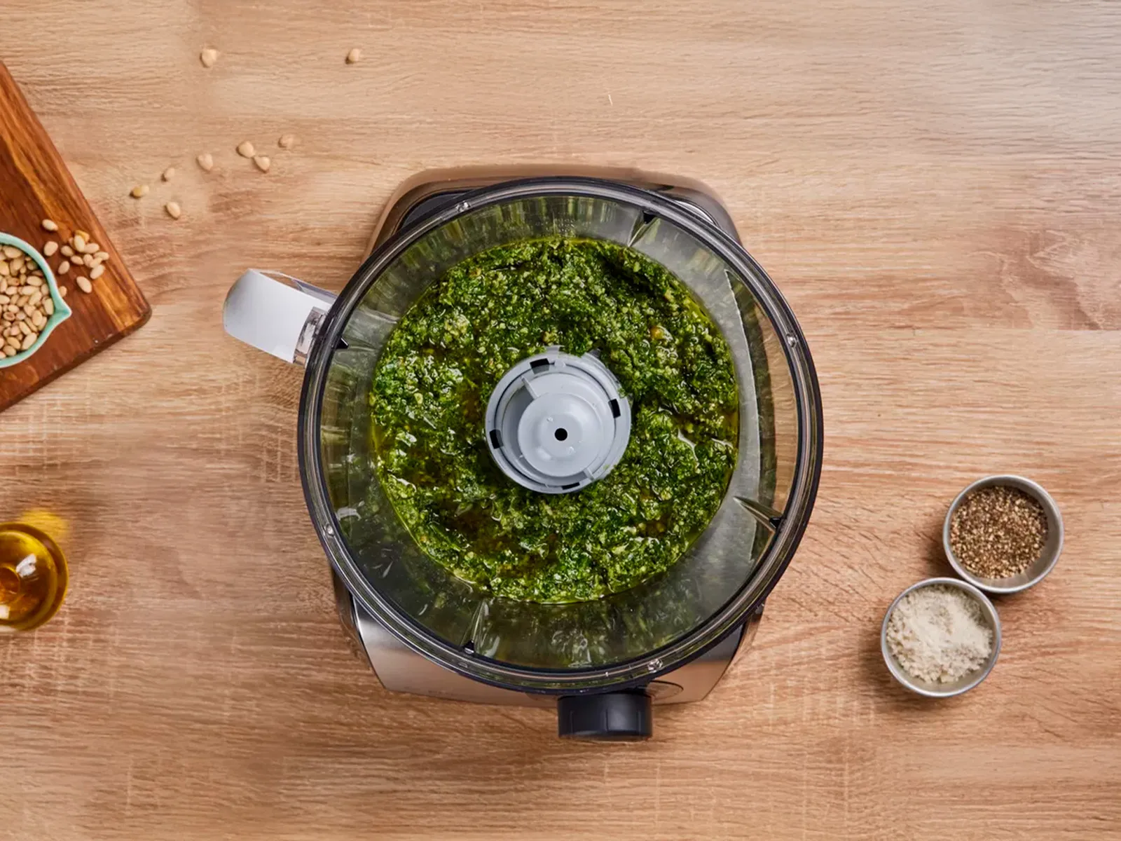 Vue plongeante de la préparation de pesto dans un robot de cuisine.