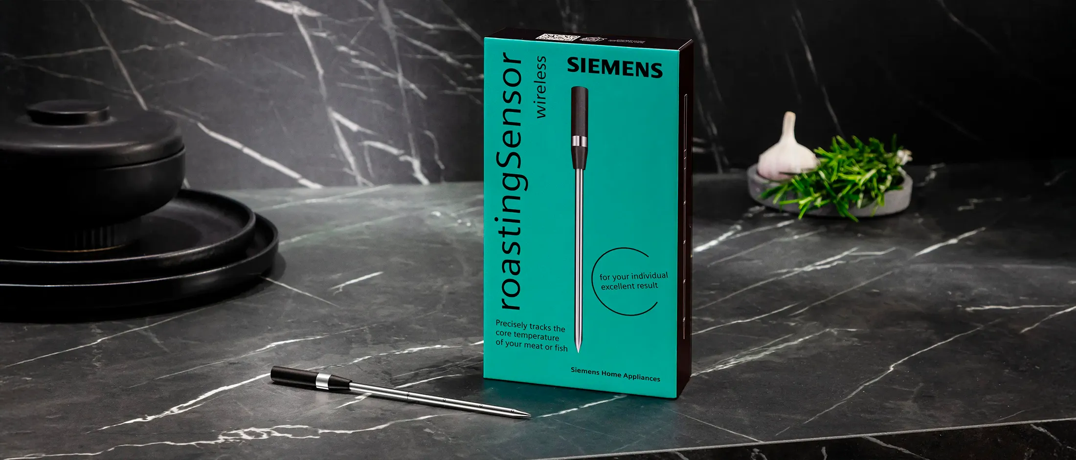 Den trådlösa rostsensorn från Siemens på en mörkgrå marmorskiva bredvid produktförpackningen.