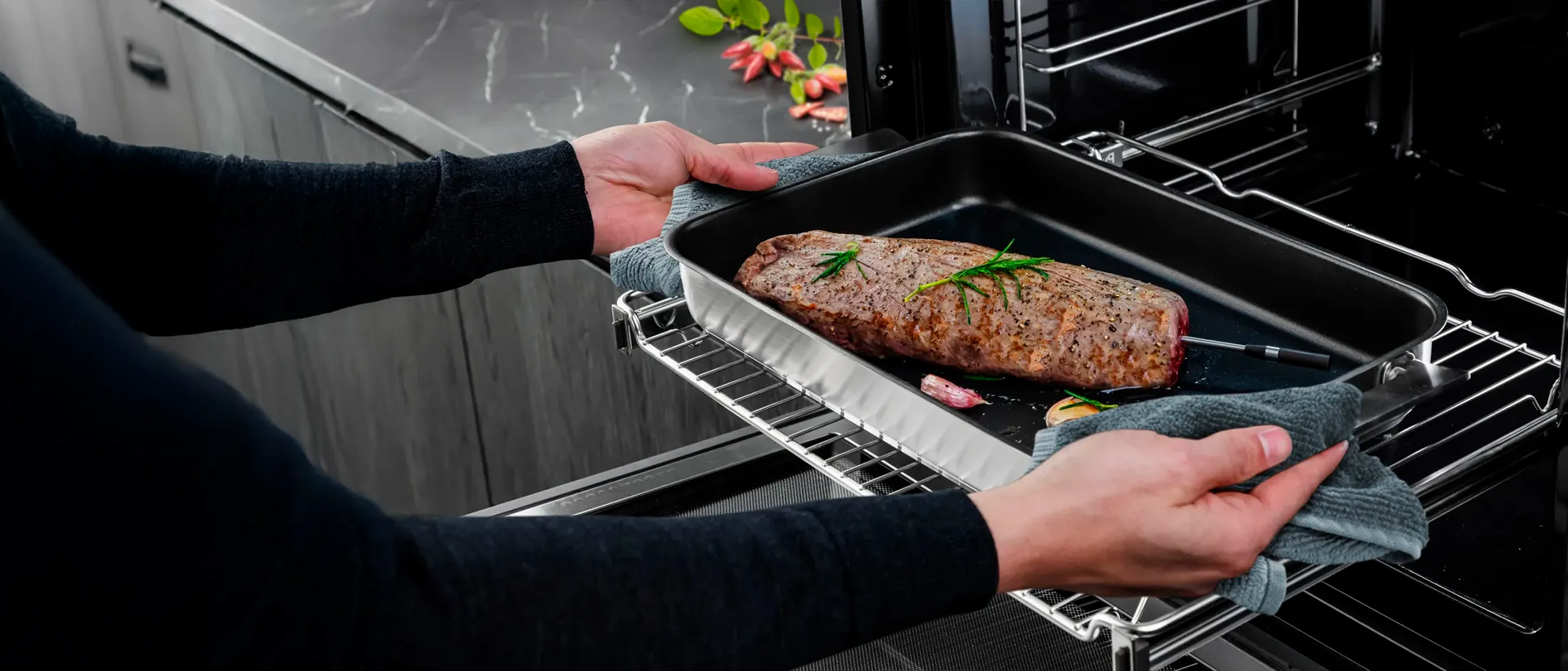 Des mains chargent un plat de viande rôtie dans un four avec le capteur de rôtissage sans fil inséré dans la viande.