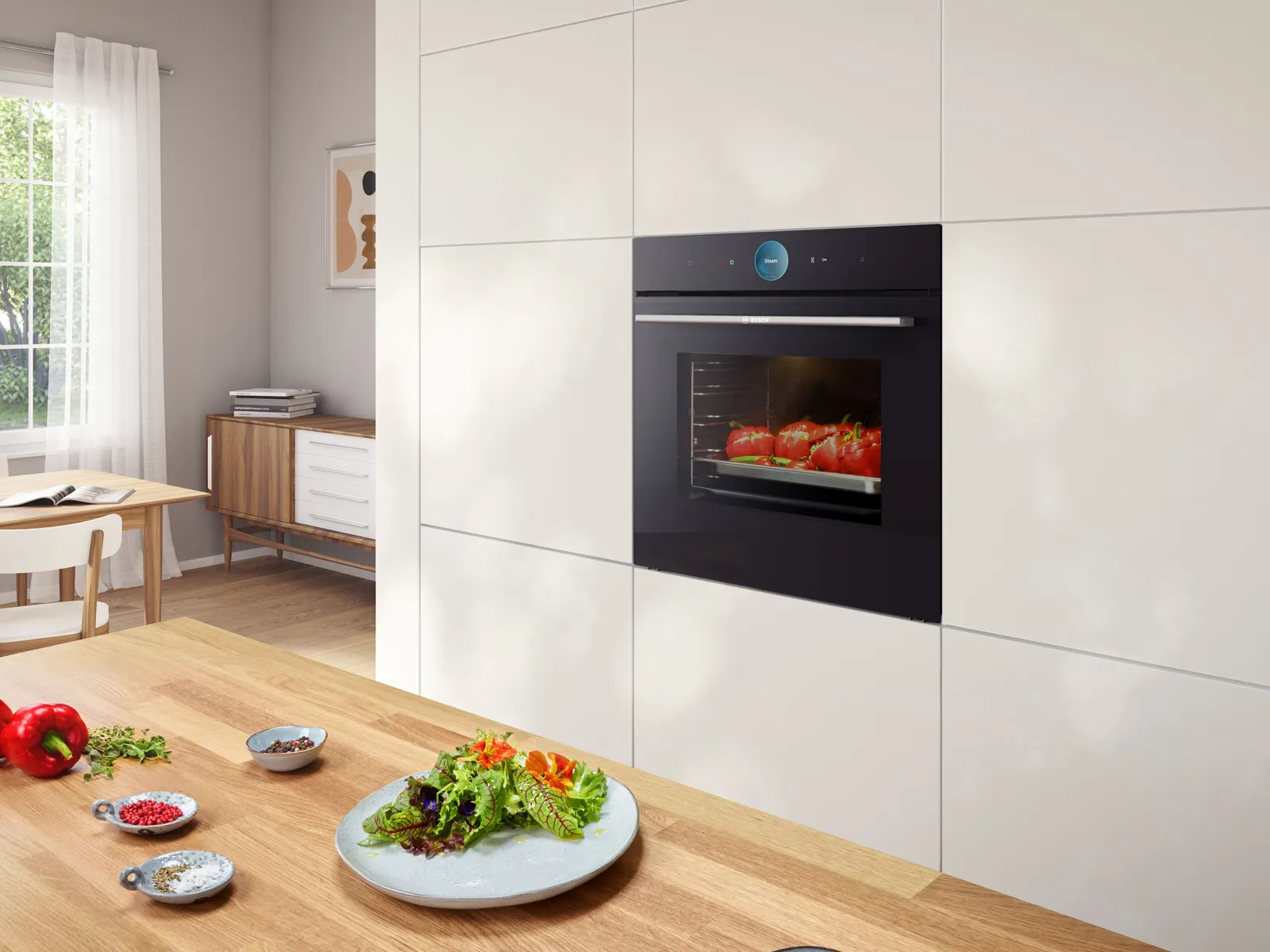 O bucătărie modernă, cu un cuptor elegant, încorporat, care gătește roșii, înconjurată de ingrediente proaspete.