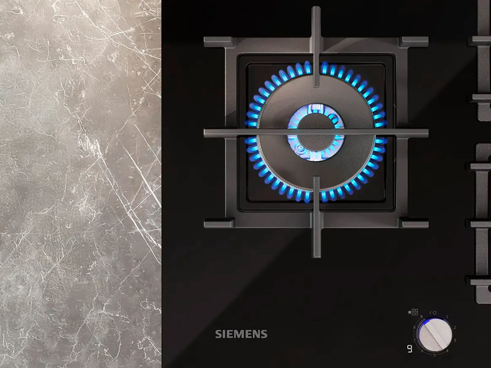 A top-down view of a lit gas burner on a Siemens gas hob.