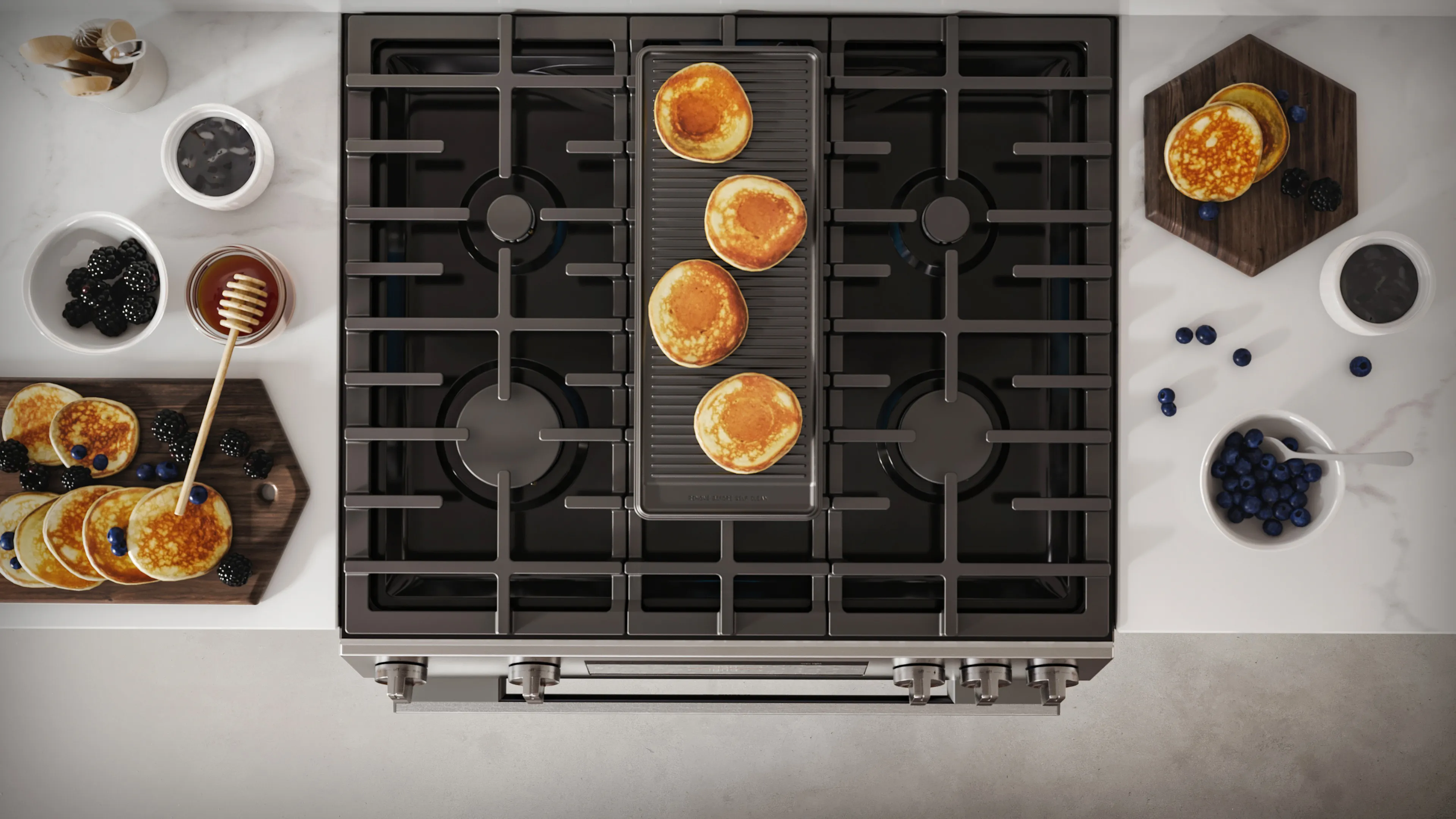 100 series gas range cooking pancakes on a griddle with cooked pancakes and blueberries on the countertop