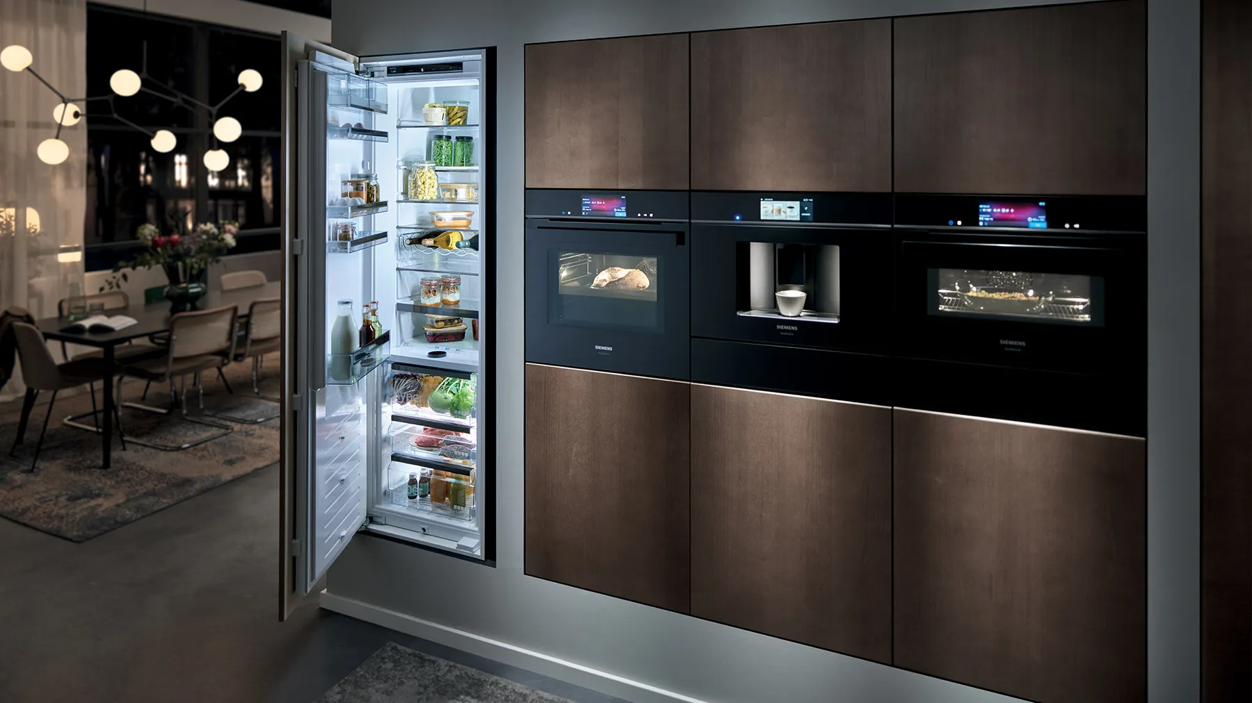 Cucina moderna con elettrodomestici da incasso, frigorifero aperto rifornito di cibo e zona pranzo visibile attraverso porte in vetro.