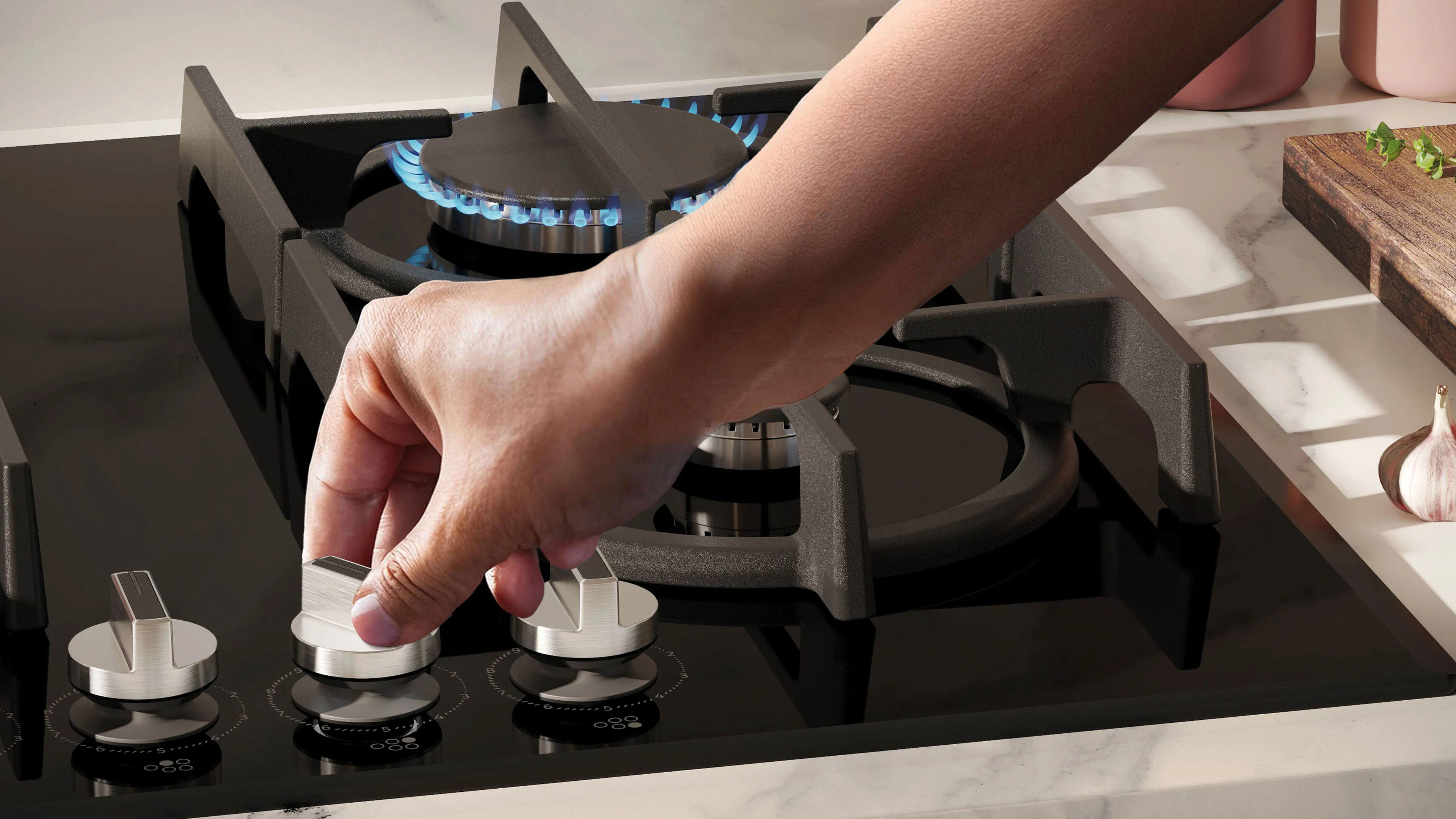 Une main ajuste le bouton de commande d'une cuisinière à gaz noire avec un brûleur à flamme bleue en arrière-plan.