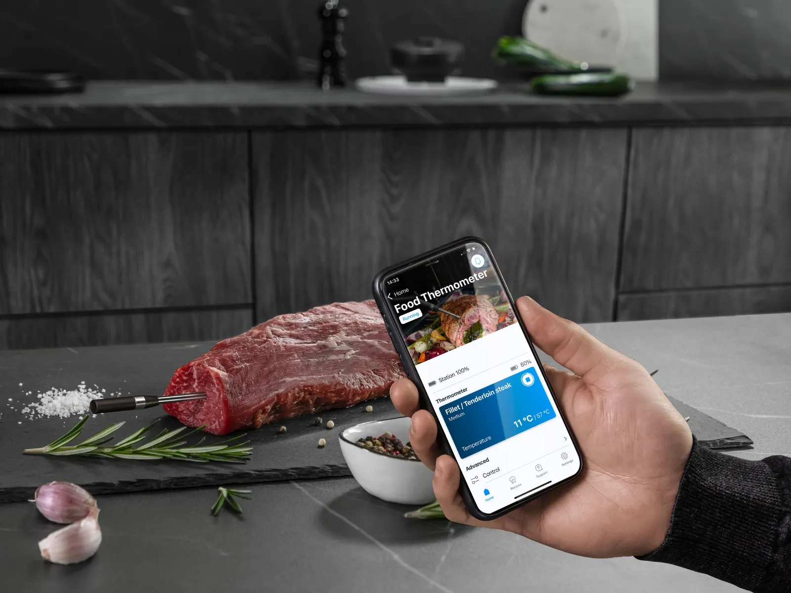 Ein Mann setzt den kabellosen roastingSensor in ein rohes Rinderfilet ein, daneben liegen Knoblauch und Kräuter.