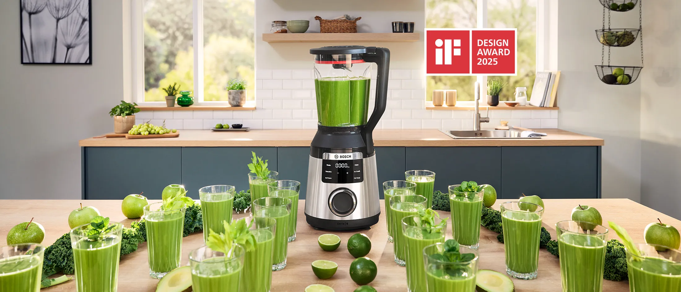 VitaPower Serie 6 cercado por linhas de copos com smoothies verdes, abacates e limões sobre a mesa da cozinha.