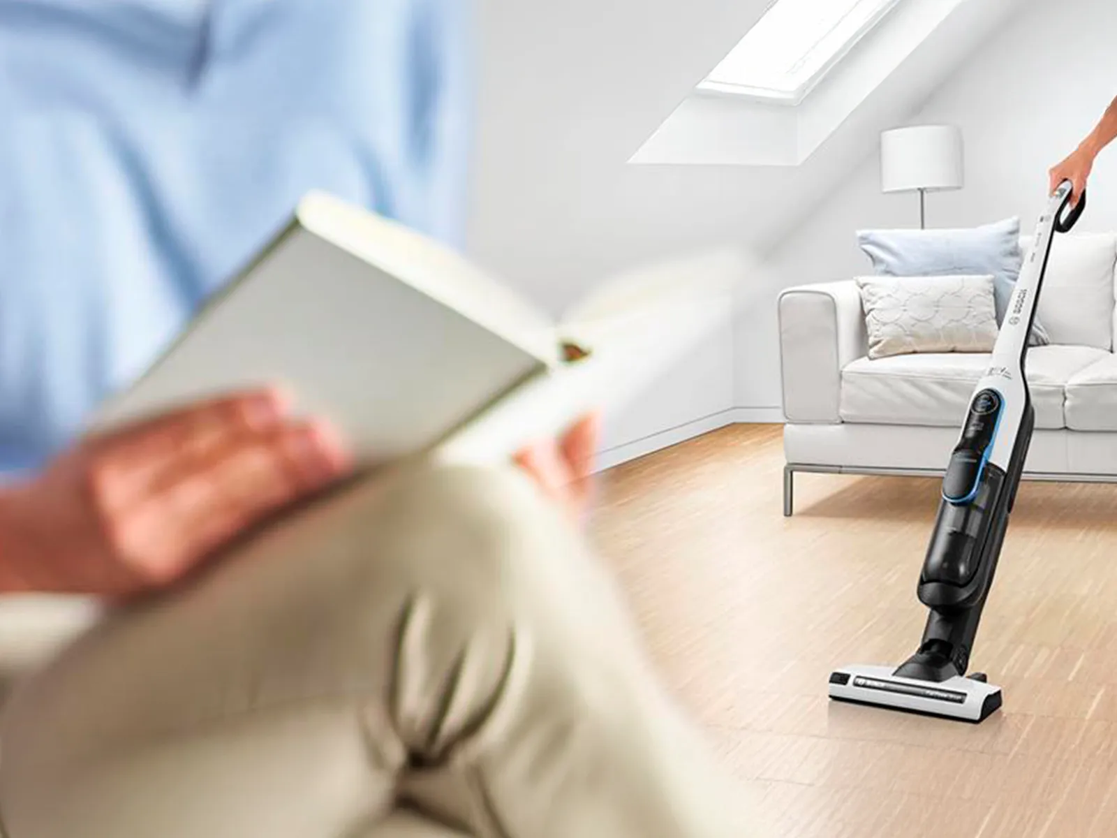 Person reads while someone vacuums in the background.
